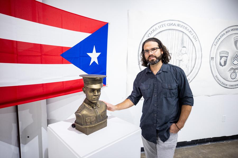 Carlos standing next to a bust of his grandfather